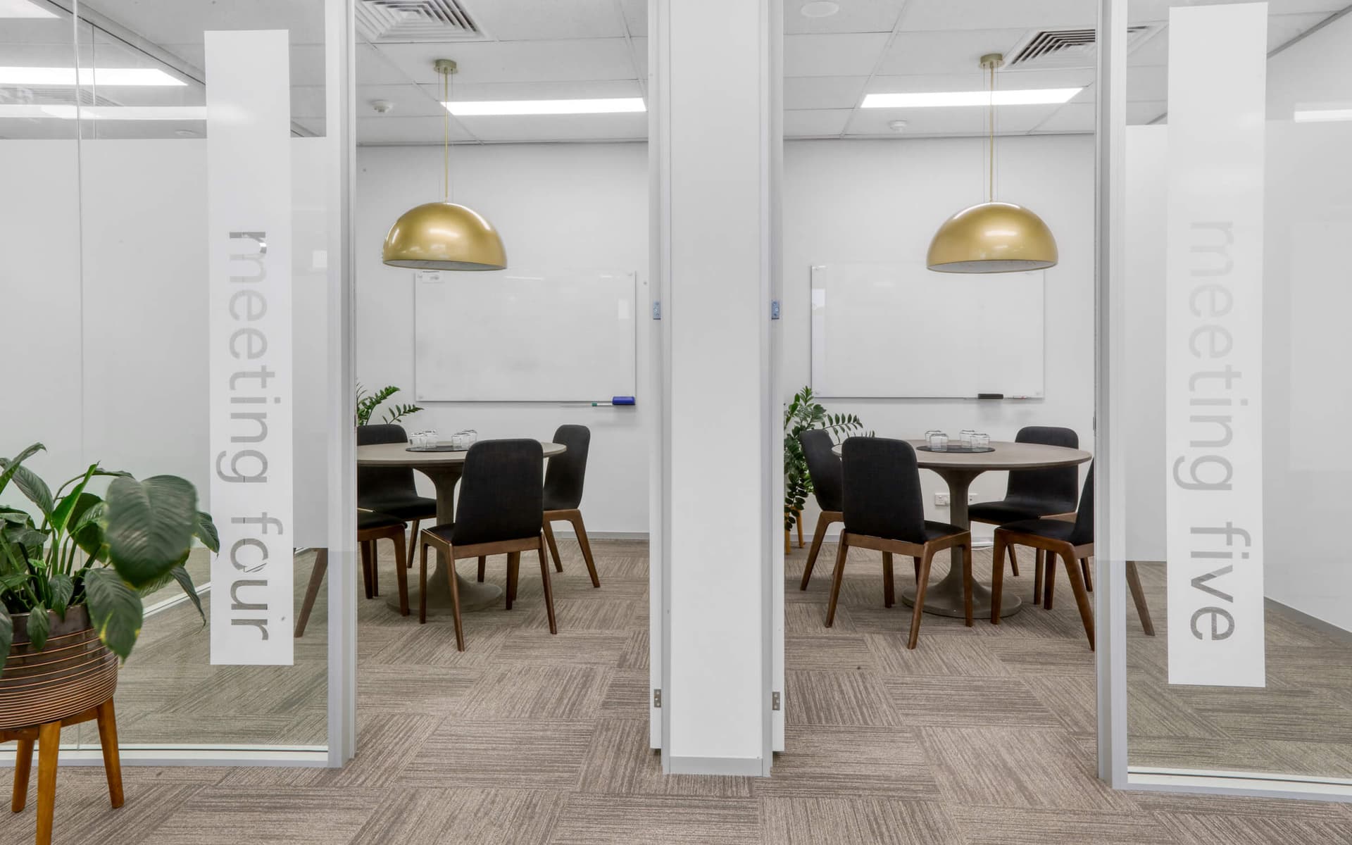 Meeting rooms "Four" and "Five" with round tables, black chairs, gold pendant lighting, and whiteboards.
