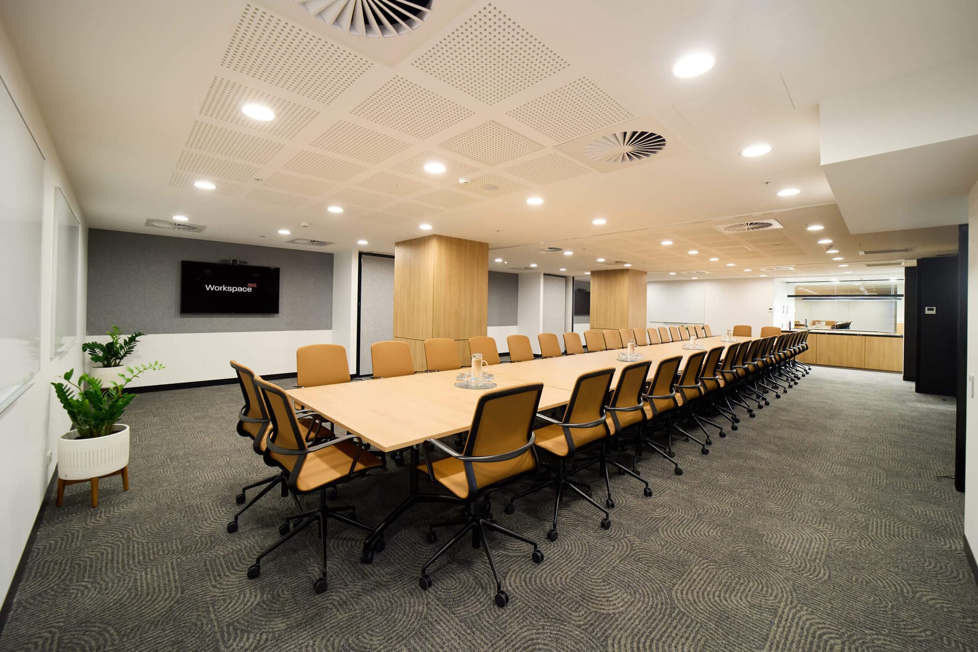 Modern conference room with a long table, chairs, and a screen displaying the word "Workspace365".